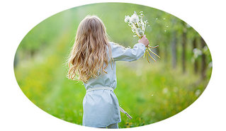 Mädchen läuft über Wiese mit Blumen in der Hand